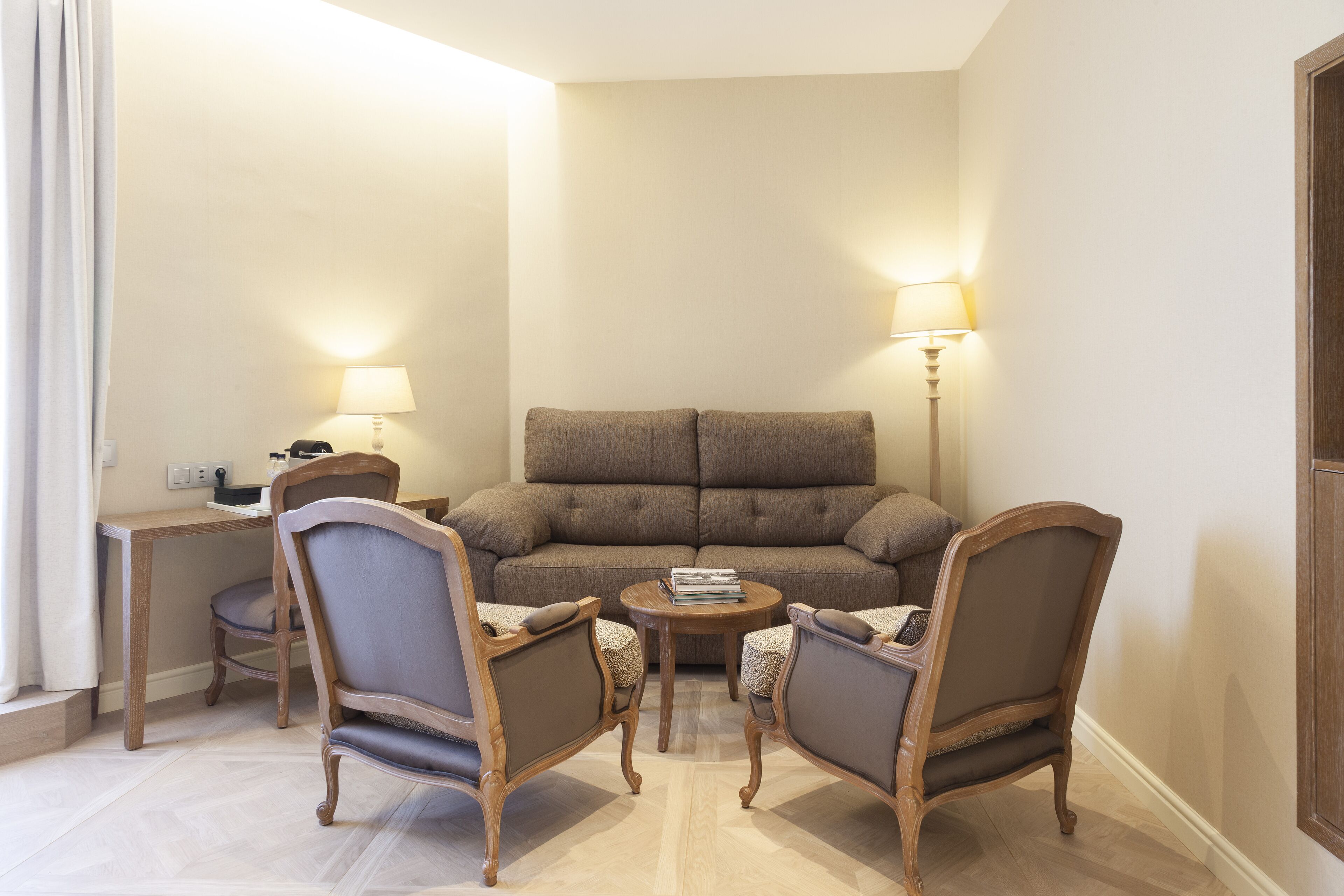 Un salon comprenant un canapé, deux fauteuils, une table basse et deux lampes.