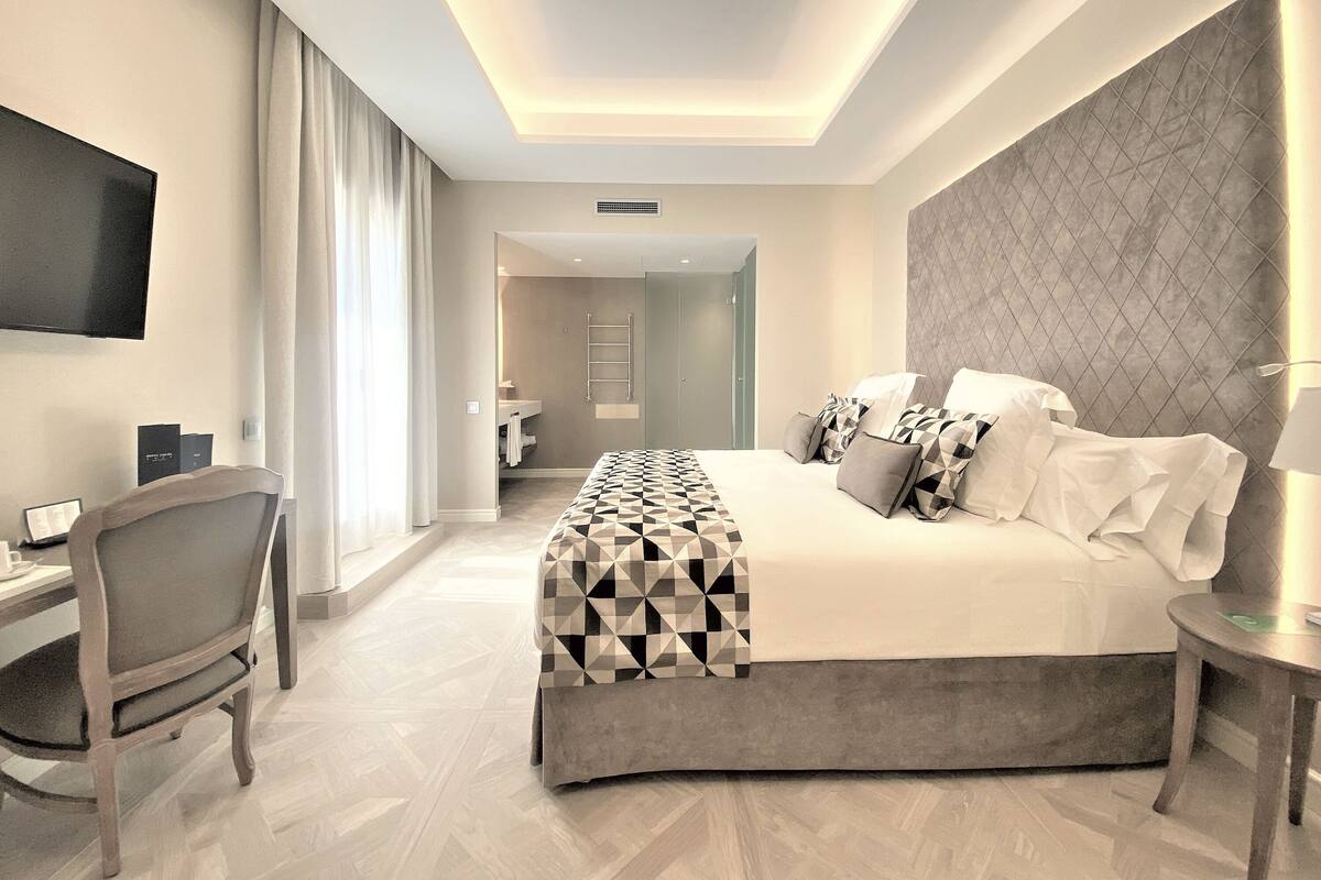 Quarto de hotel moderno com uma cama grande, uma escrivaninha e uma televisão.