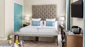 A hotel room with a large bed, bedside tables with lamps, a desk with a coffee maker, and a TV on the wall.