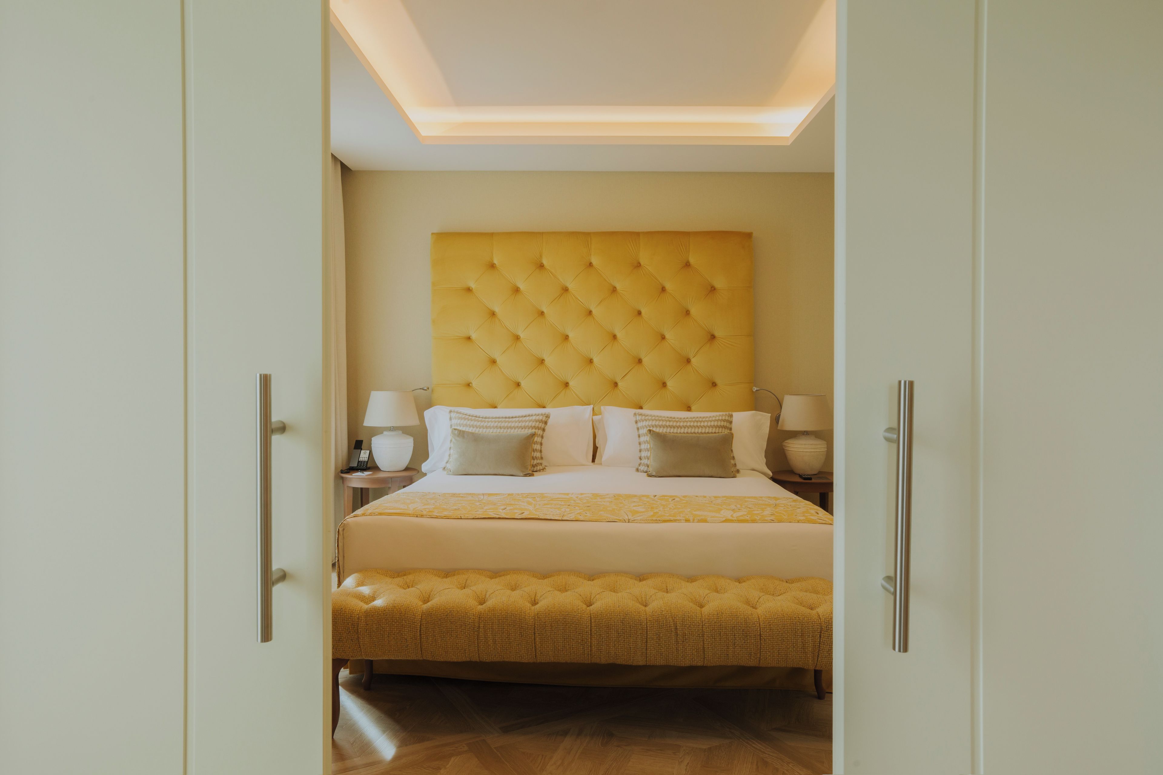 A hotel room with a large bed, a tufted headboard, and bedside lamps.