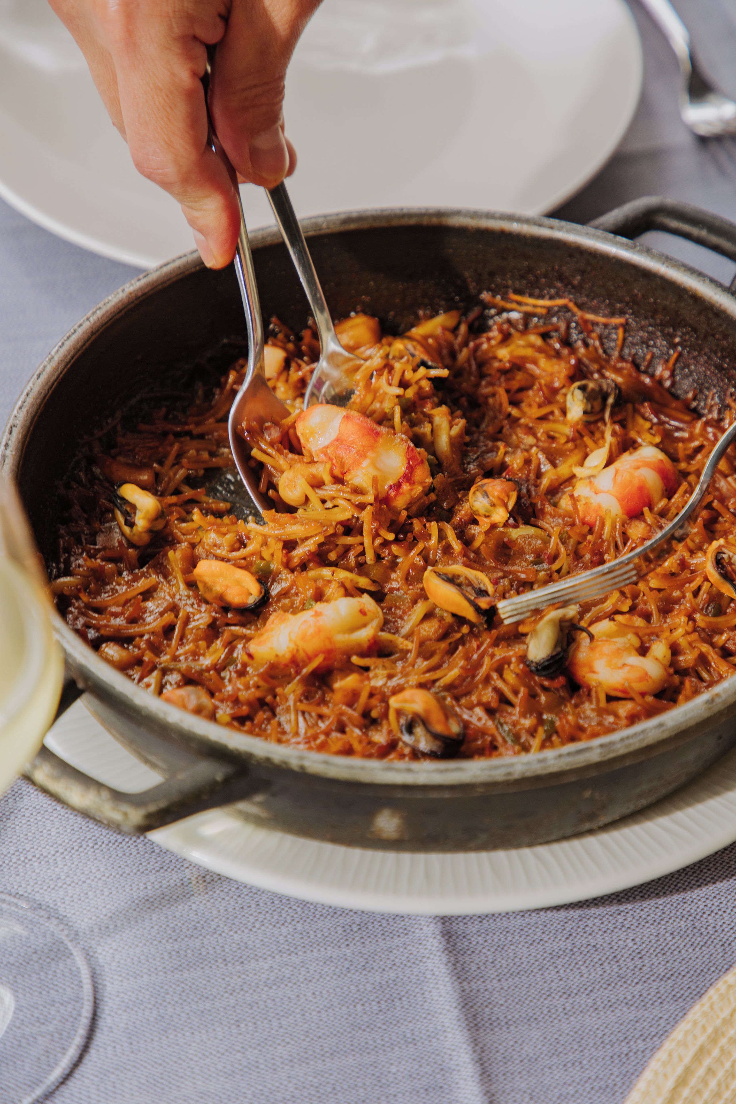 En närbild på en paella med skaldjur som serveras med en sked.