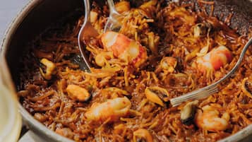 En närbild på en paella med skaldjur som serveras med en sked.