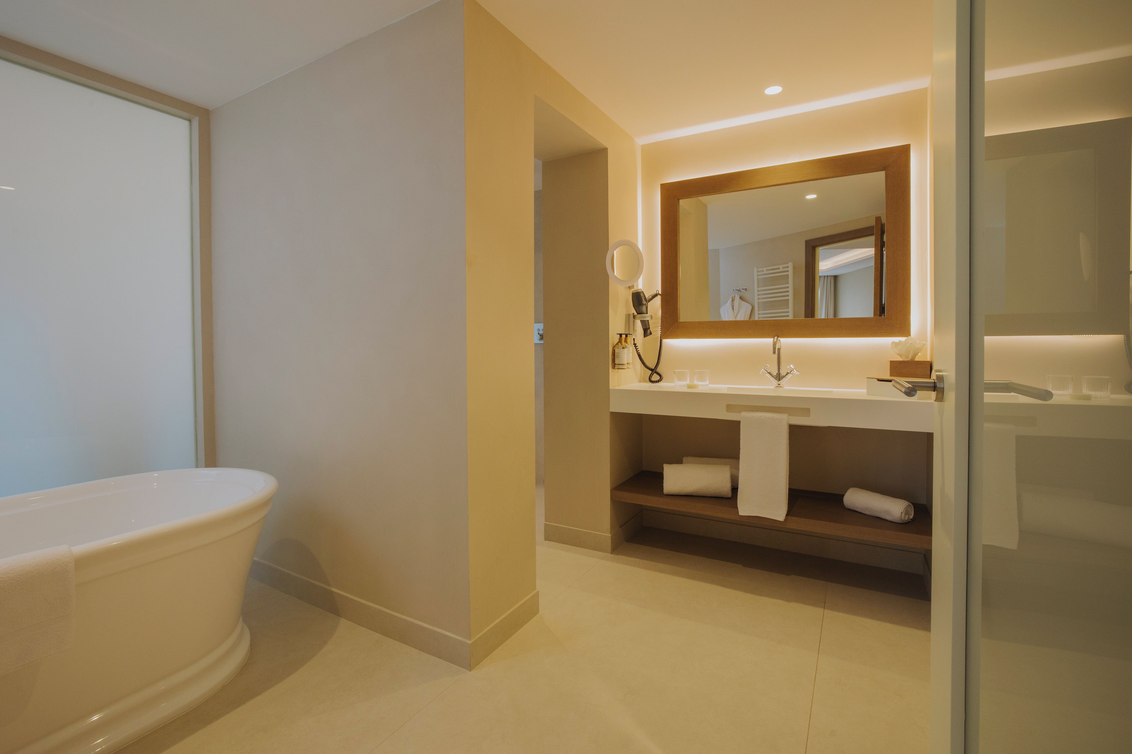 A modern bathroom with a freestanding bathtub, a vanity with a mirror, and a towel rack.