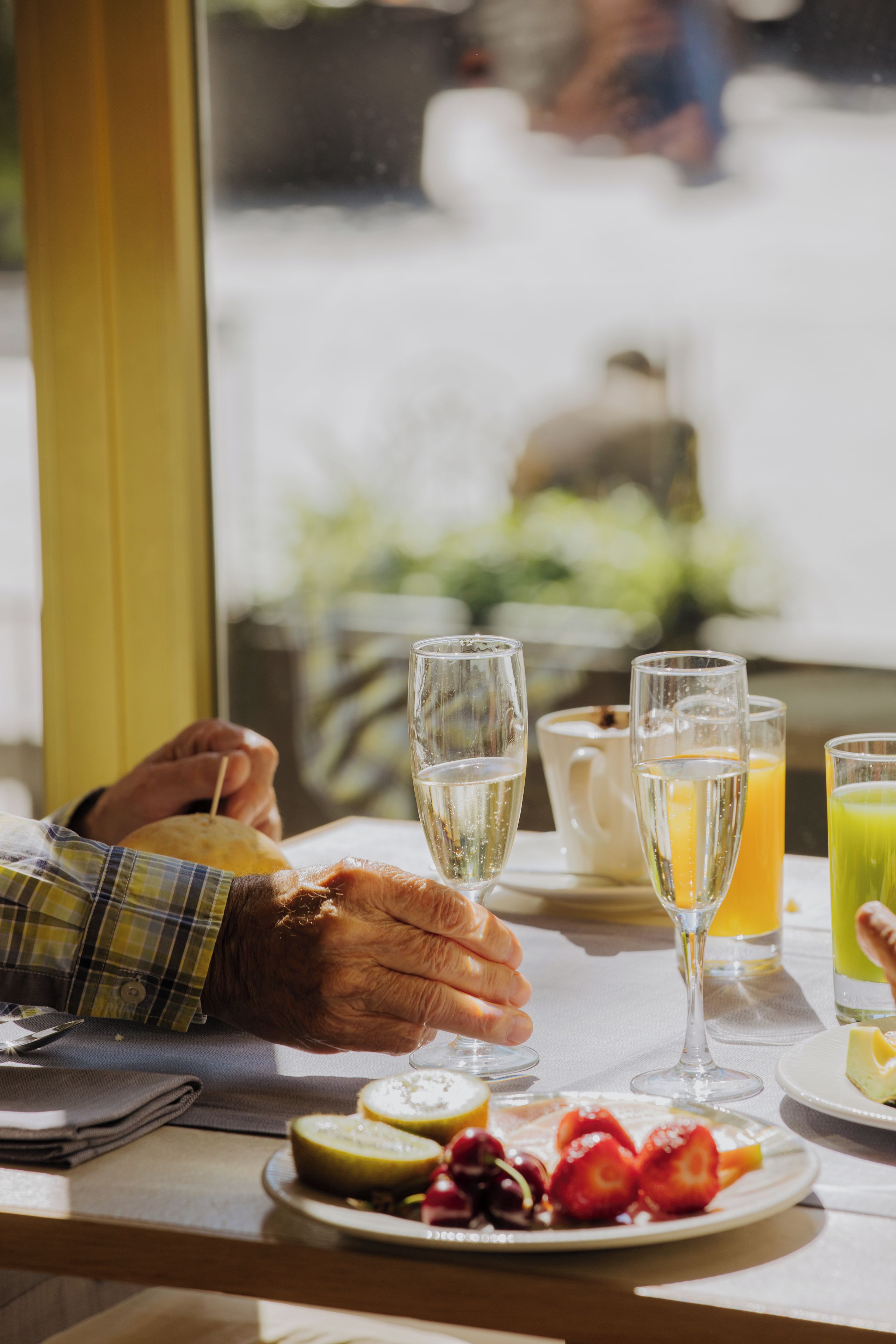 A breakfast setting with a table, plates of fruit, and glasses of beverages.