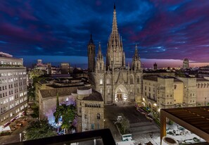 Una catedral gótica con múltiples agujas, rodeada de edificios urbanos y un cielo despejado.