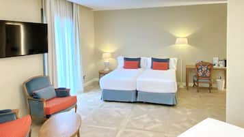 Habitación de hotel con cama, dos mesitas de noche, televisor, escritorio con silla y ventana con cortinas.