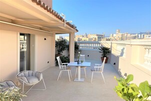 Un balcon avec une table et des chaises, des plantes en pot et une vue sur le paysage urbain.
