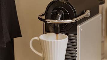A person operating a coffee machine, with a white cup placed underneath the spout.