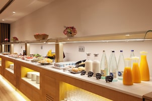 A buffet setup with various food items, beverages, and a glass display case.