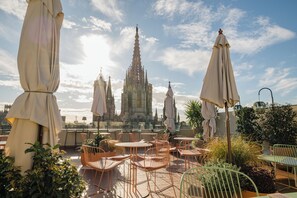 Terraço no telhado com área de estar externa e vista para uma catedral.
