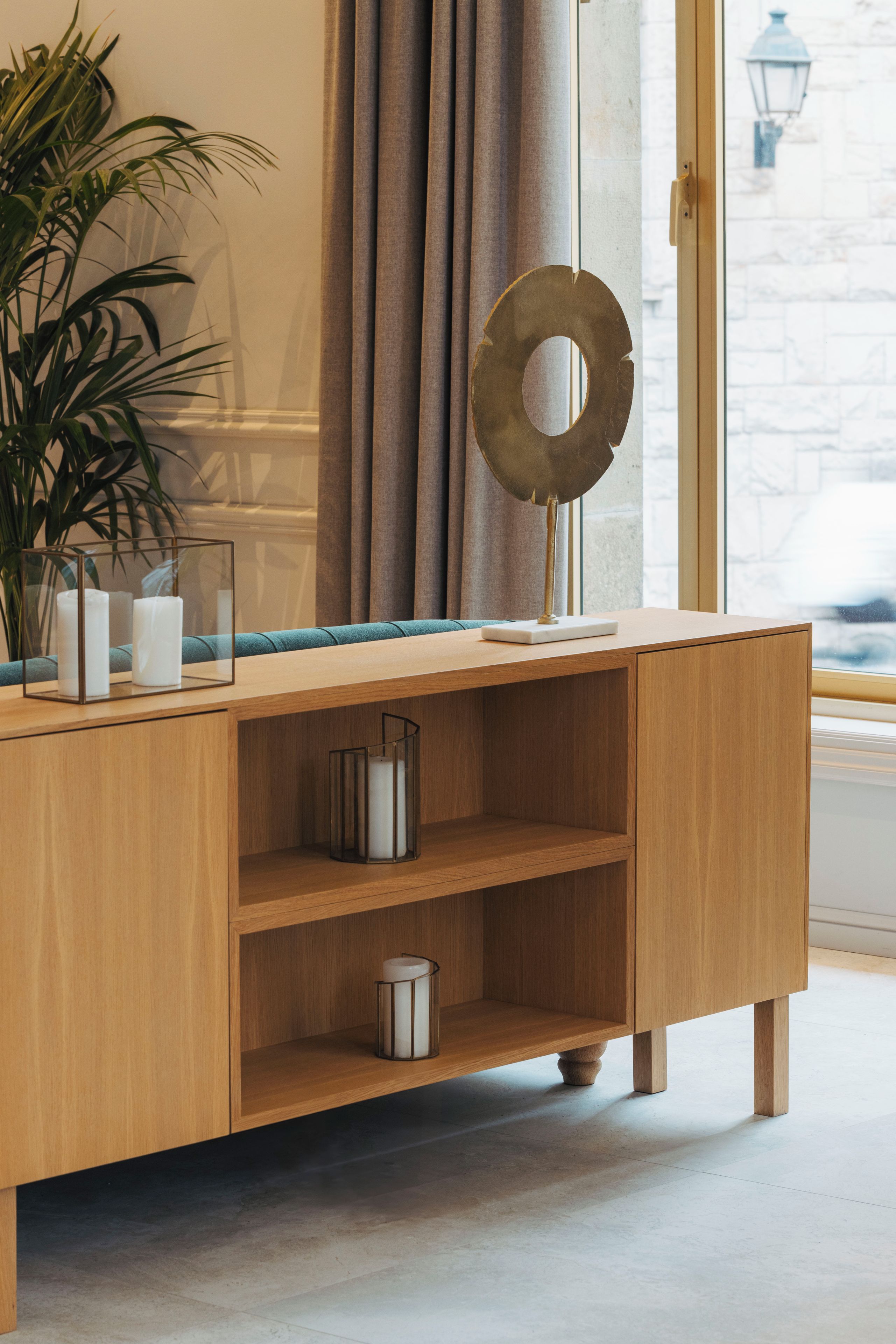 A wooden console table with shelves, a potted plant, and decorative items.