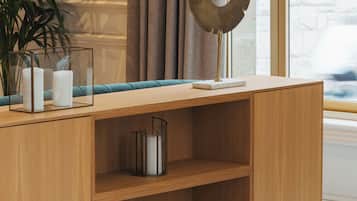 Una consola de madera con estantes, una planta en maceta y objetos decorativos.