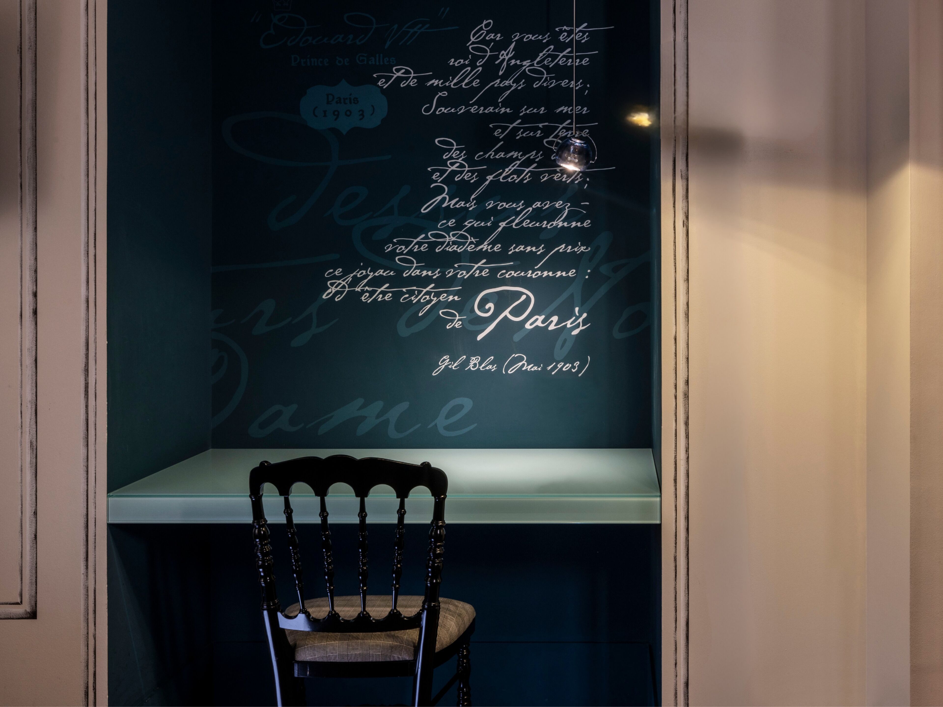 A wall with a quote in cursive script, a chair, and a table.