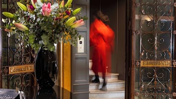 A hotel entrance with a sign reading 'Edouard VII' and a person in red walking up the stairs.