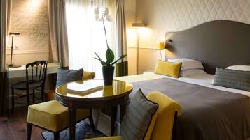 Habitación de hotel con cama, escritorio, silla, mesa y planta en maceta.