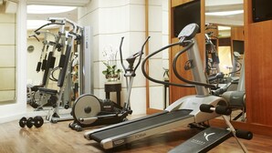 A home gym with a treadmill, elliptical, and weight machines. - Hôtel Edouard 7 Paris Opéra (Paris)