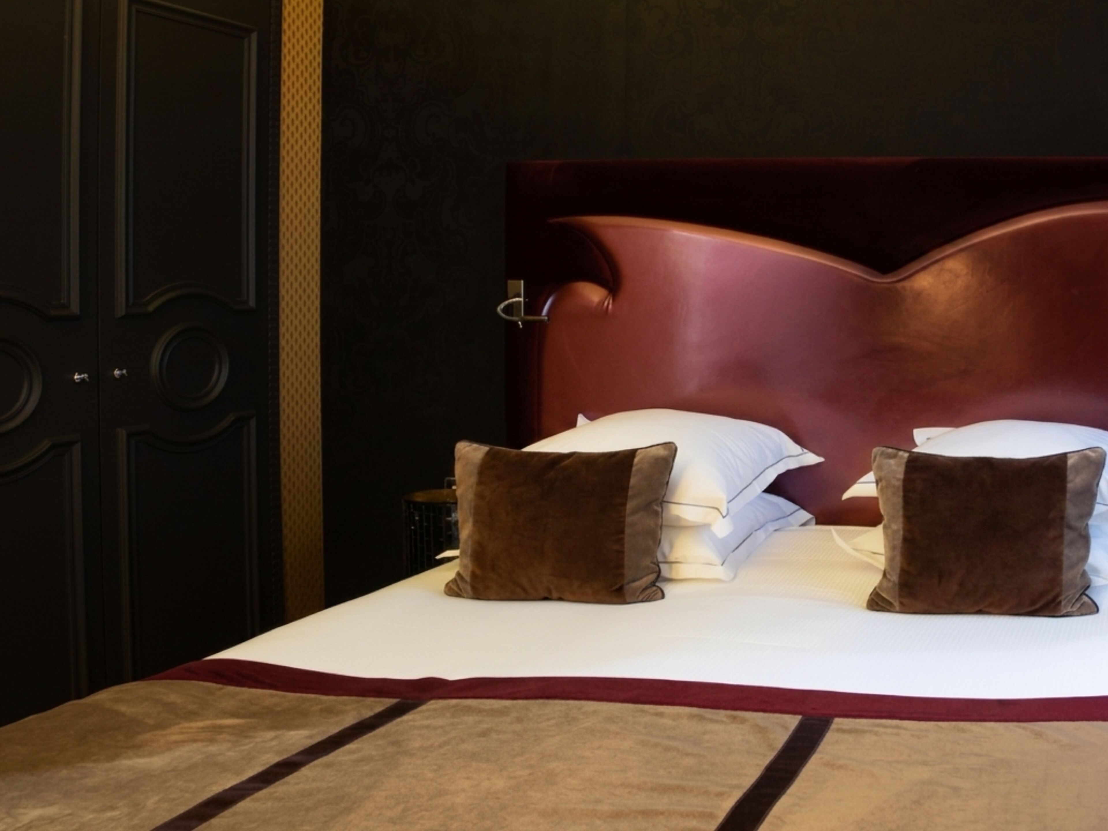 Uma cama com cabeceira, travesseiros e mesa de cabeceira.