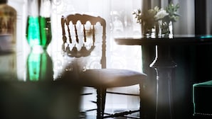 A chair with a high backrest and a cushioned seat, positioned near a table with a vase of flowers. - Hôtel Edouard 7 Paris Opéra (Paris)