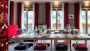 A conference room with a long table, clear chairs, and red cushions. - Hôtel Edouard 7 Paris Opéra (Paris)