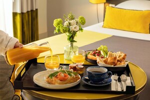 A breakfast tray with a croissant, ham, and a glass of orange juice.