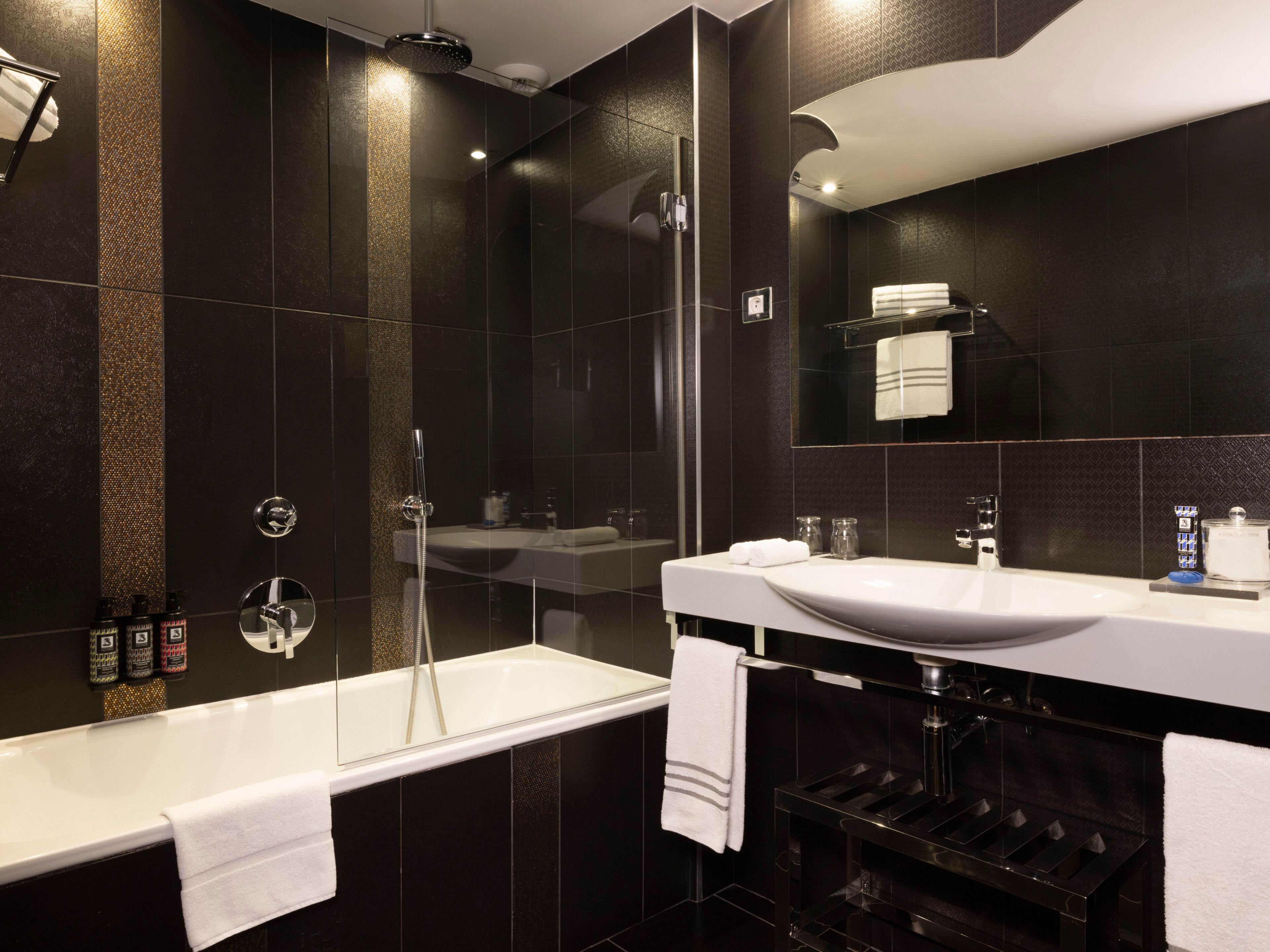 A modern bathroom with a bathtub, a glass-enclosed shower, and a vanity with a sink and mirror.