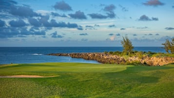 A golf course with a view of the ocean and rocky coastline.