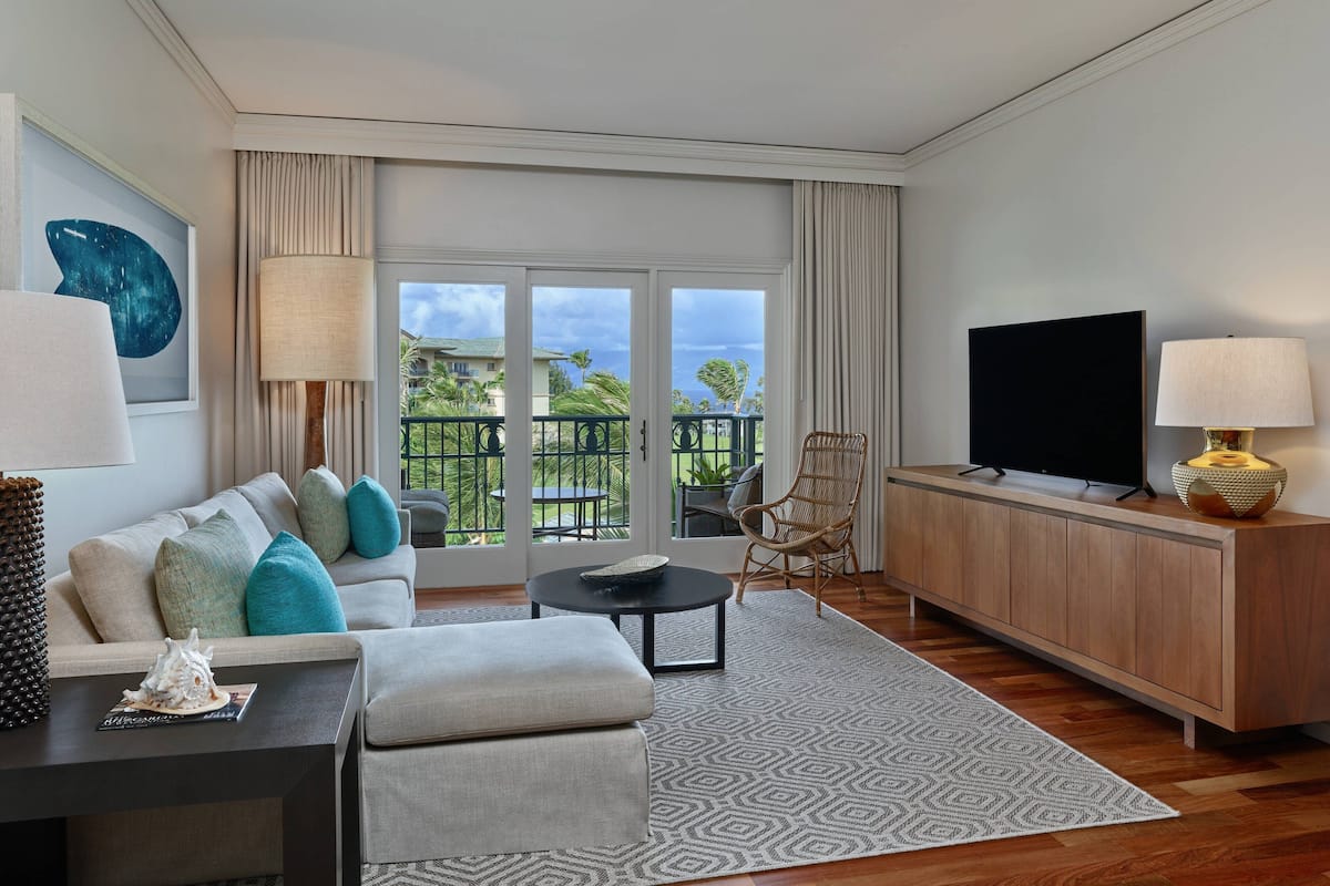 A modern living room with a sofa, ottoman, coffee table, and a TV on a wooden cabinet.