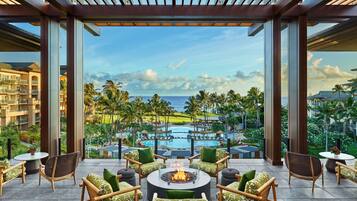 Relax in style with a fire pit at the center of this outdoor seating area, surrounded by wicker chairs and lush views of the tropical resort.