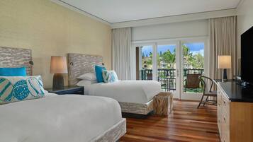 A hotel room with two beds, a desk, and a view of the outdoors.