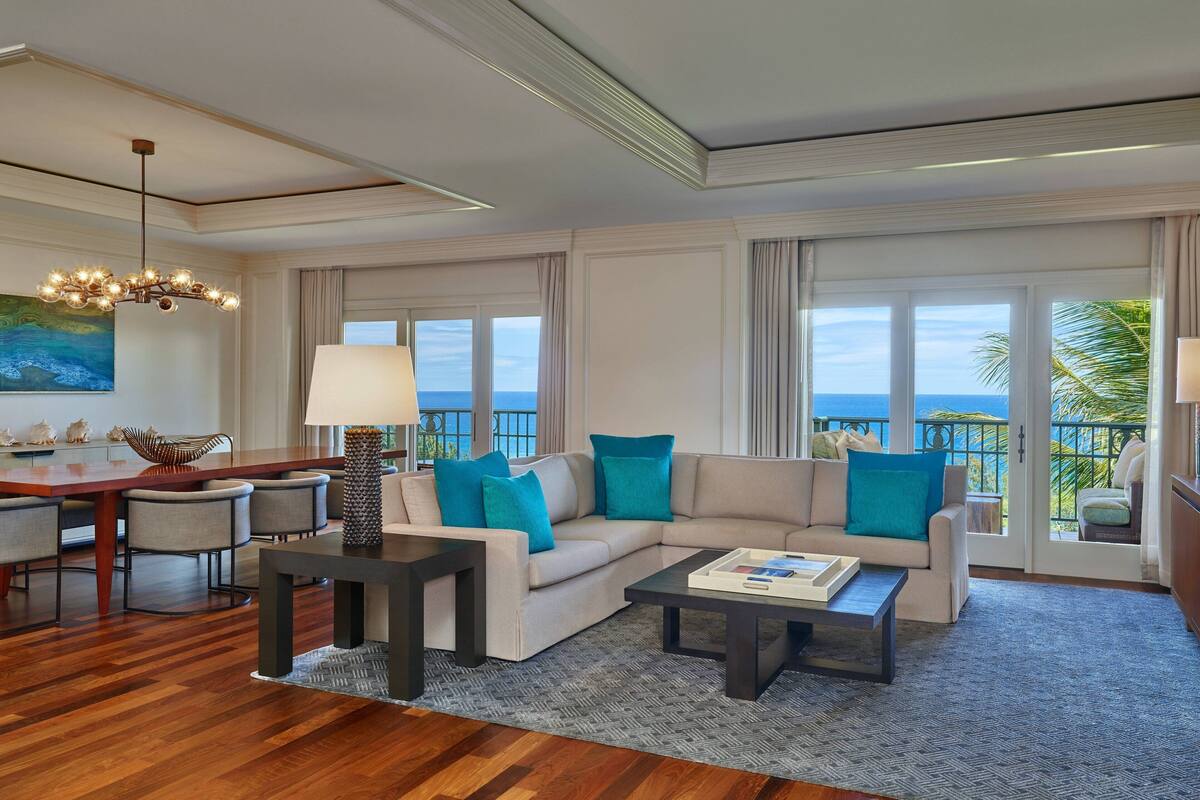 A spacious living room with a large window, a sofa, a coffee table, and a dining area.