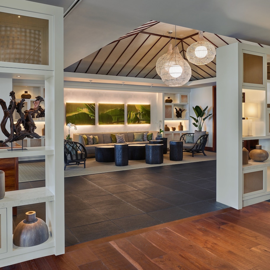 A spacious living area with a high ceiling, modern furniture, and decorative shelves.