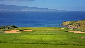A golf course with a view of the ocean and distant mountains.