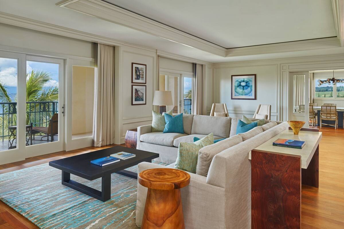 A spacious living room with a large sofa, a coffee table, and a view of the outdoors.