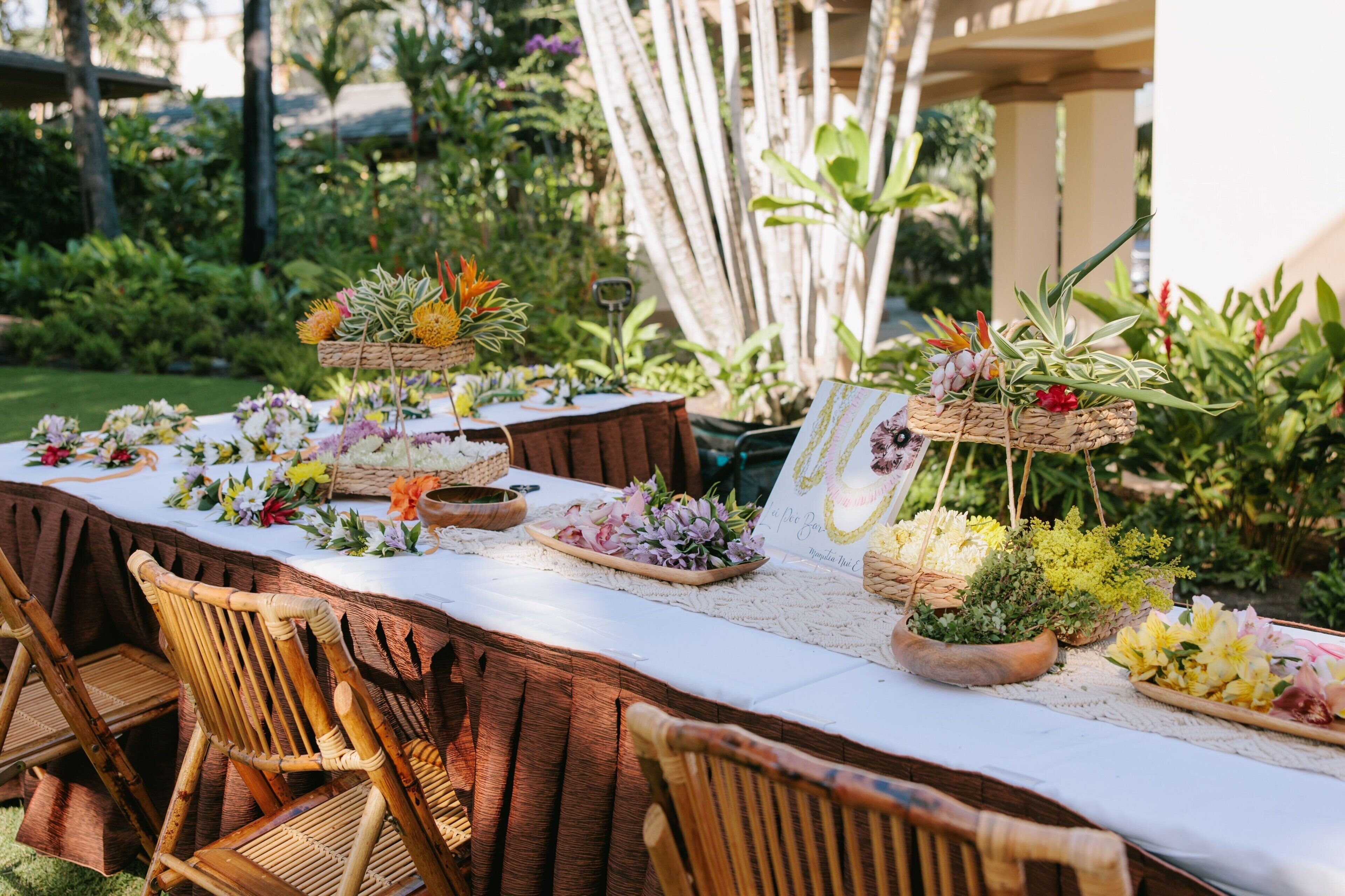 Un área de comedor al aire libre con una larga mesa dispuesta con diversos platos y arreglos florales.