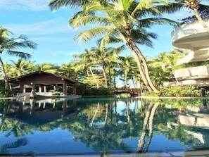 A clear view of a swimming pool surrounded by palm trees and a building with a covered patio area. - ParkCity Everly Hotel Miri (Miri)