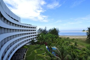 Um hotel moderno com fachada curva, piscina e vista para a praia.