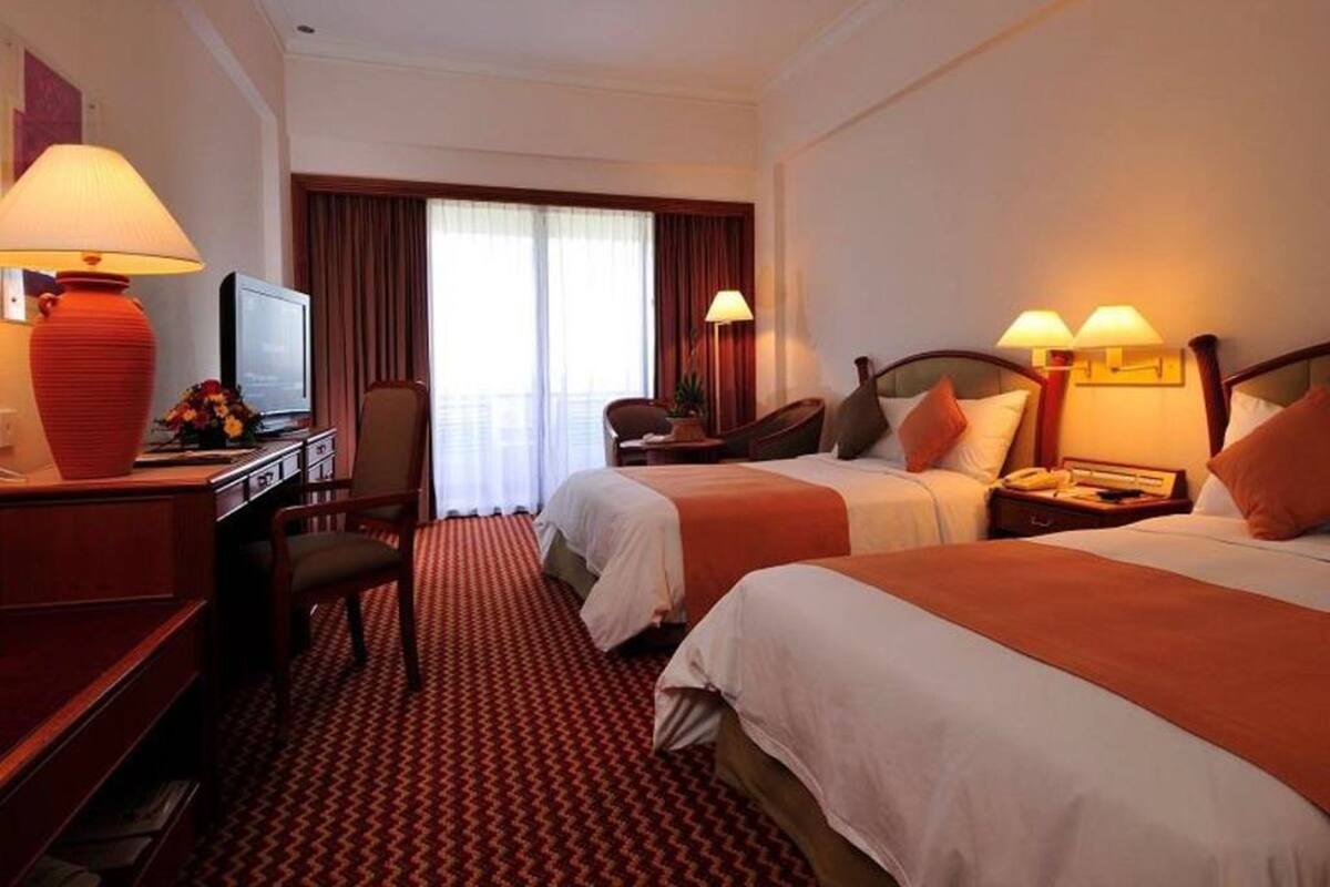 Habitació d'hotel amb dos llits, una taula de treball i una televisió, i una làmpada vermella.
