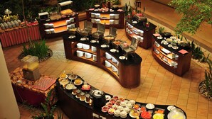 A buffet setup with multiple food stations, including hot and cold dishes, arranged in a spacious area with tiled flooring and surrounded by potted plants. - ParkCity Everly Hotel Miri (Miri)