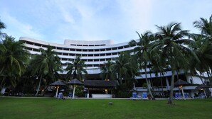 A modern hotel with a curved facade, surrounded by palm trees and a well-maintained lawn. - ParkCity Everly Hotel Miri (Miri)