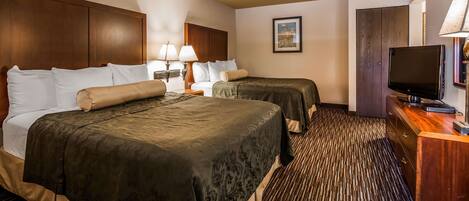 A hotel room with two beds, a television, a desk, and a carpeted floor.