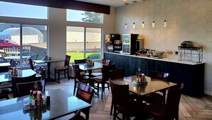 A restaurant with outdoor seating, a counter with a coffee machine, and a view of a parking area.