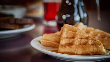 A plate of waffles with syrup on a table.