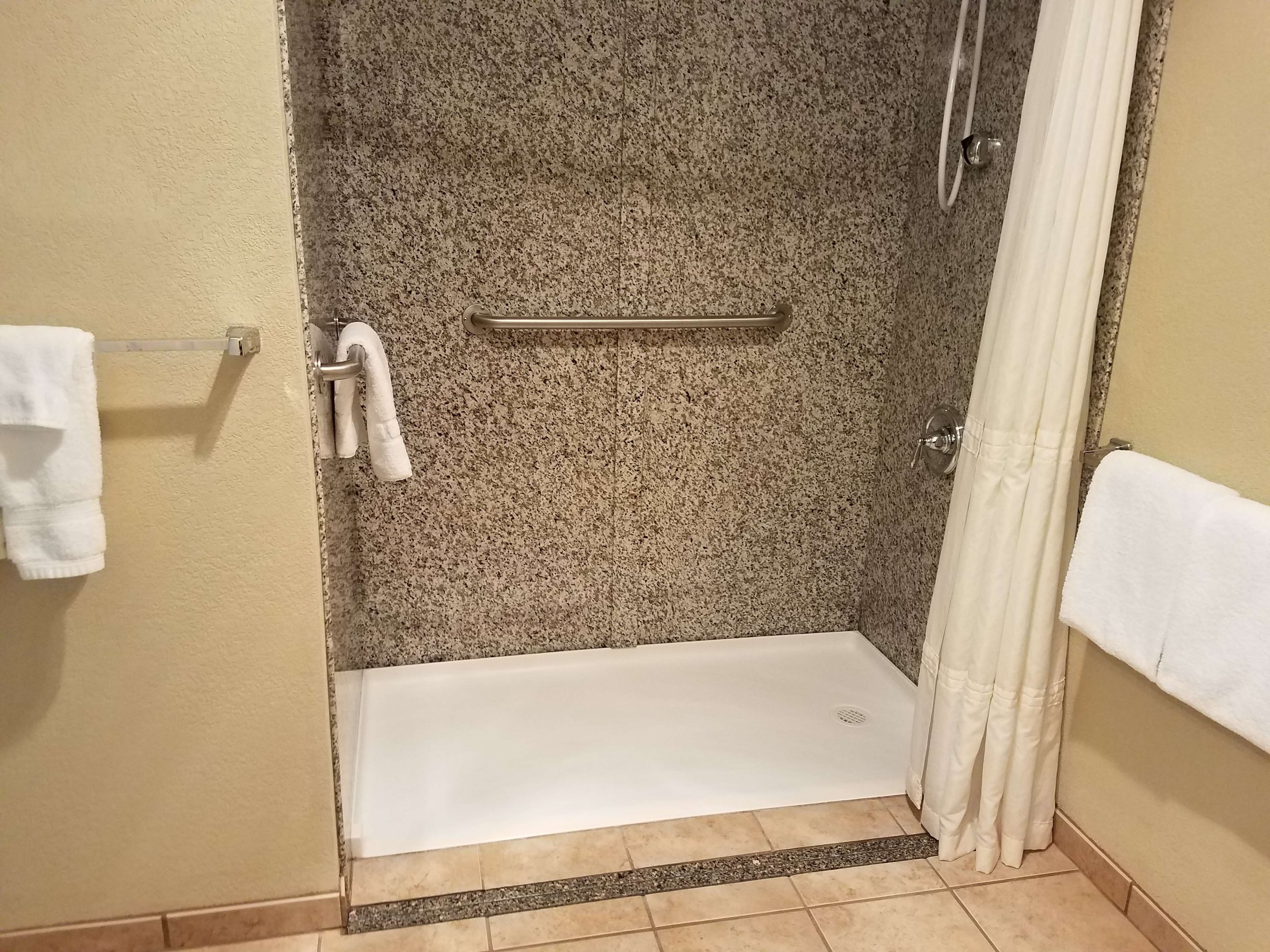 Un espace douche doté d’une porte en verre, d’un porte-serviettes et d’un rideau de douche.