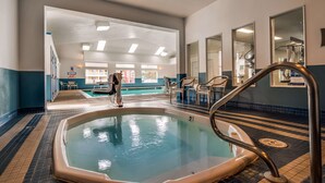 An indoor swimming pool with a tiled floor, a lifeguard chair, and a pool ladder.