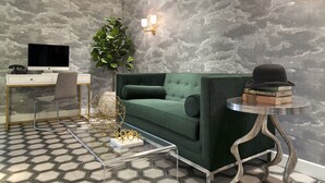 Una sala de estar moderna con un sofá verde, una mesa de centro de cristal, un escritorio con una computadora y una planta.