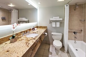 Un baño moderno con encimera de granito, lavamanos, inodoro y bañera.