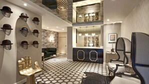 Un interior de varios niveles con un suelo de estampado geométrico, una zona de estar central con una silla original, y una pared decorada con sombreros.