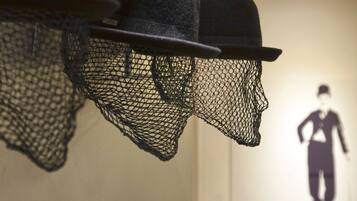 A wall with multiple black hats and a silhouette of a person.