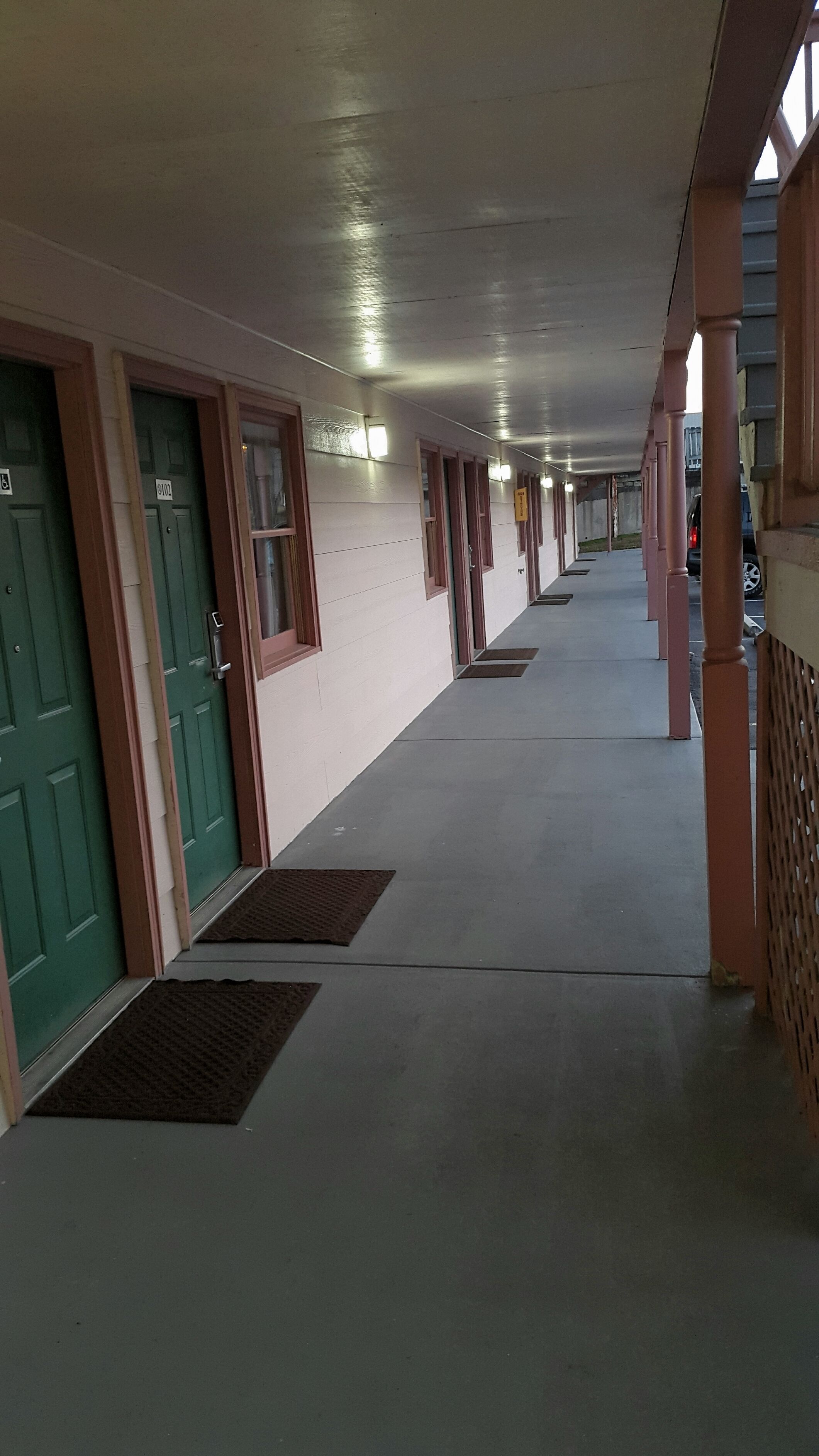 En overdækket gang med døre, vinduer og en beton gulv.