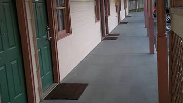 En overdækket gang med døre, vinduer og en beton gulv.